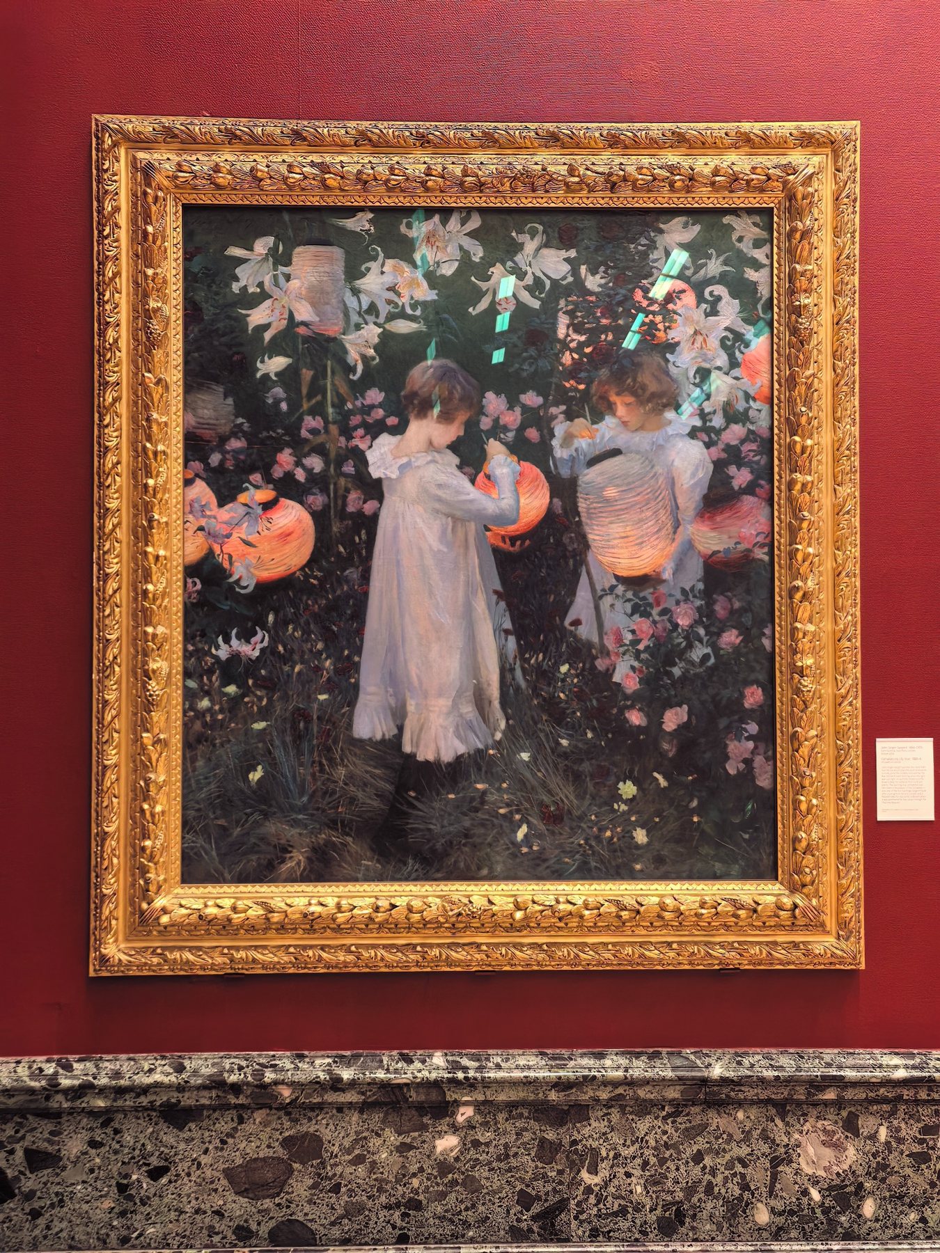 A framed painting displayed against a deep red gallery wall.