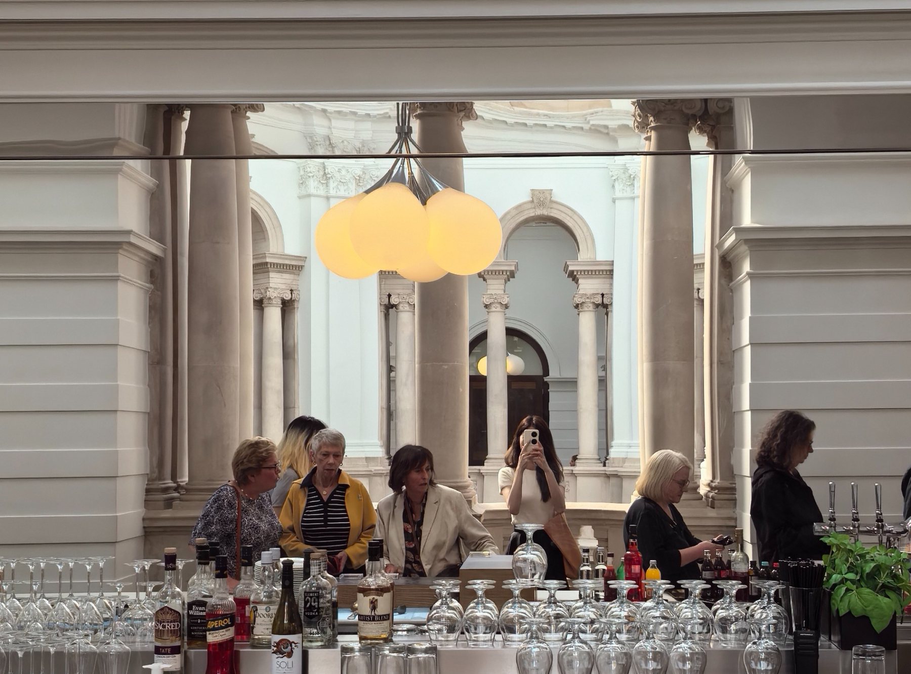A mirrored bar interior with people and rows of glassware.