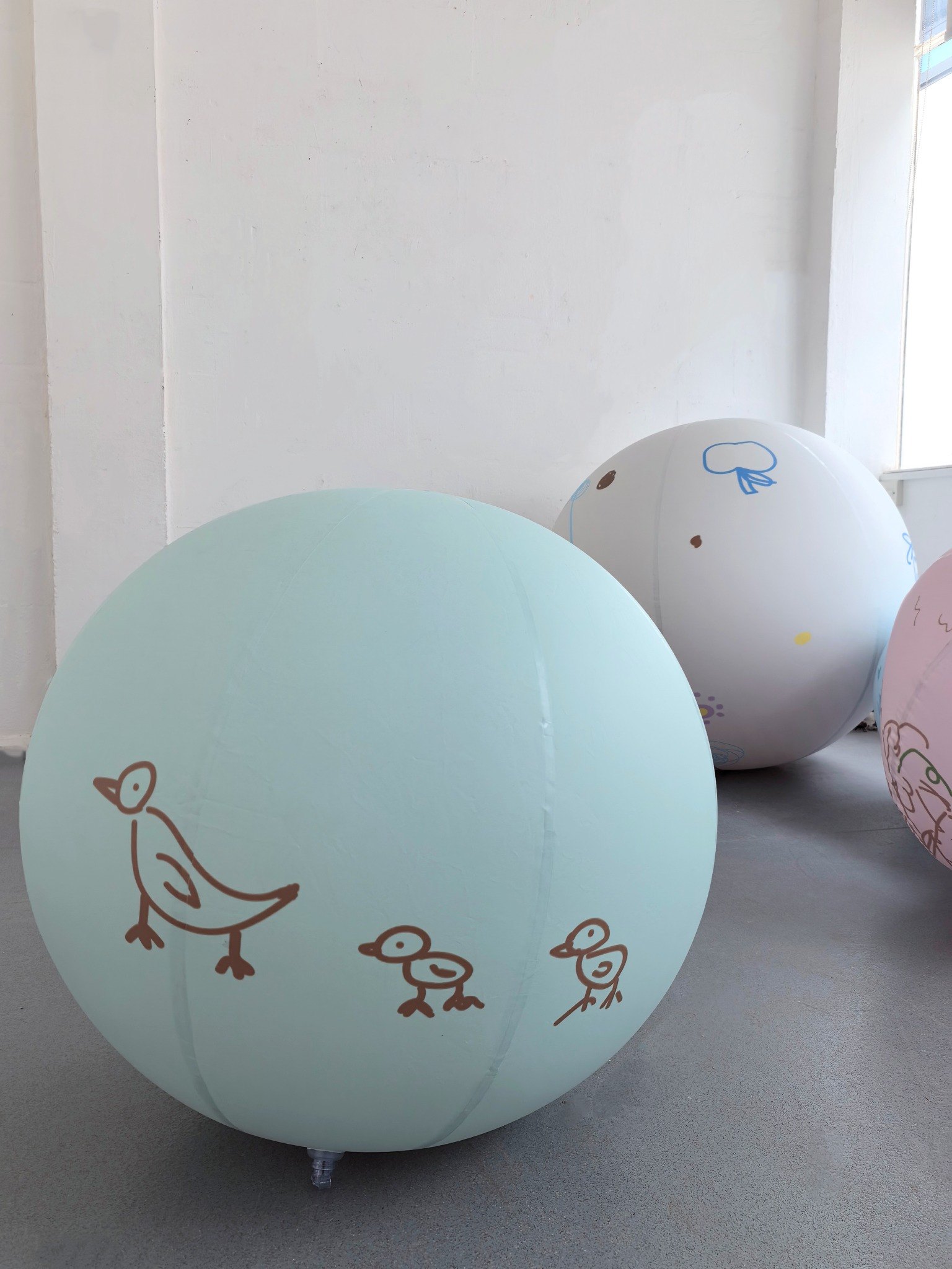 Large soft inflatable forms with participant drawings rest together in a studio.